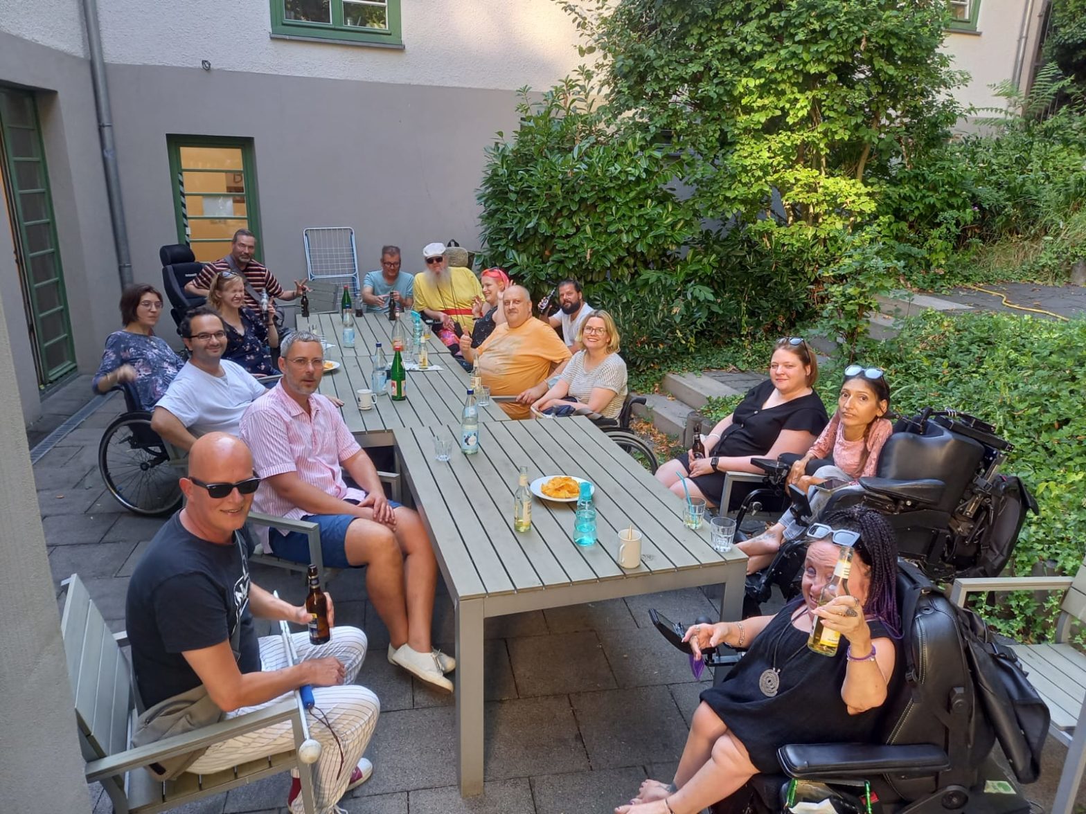 Die Teilnehmer des Grillfestes sitzen alle an einem großen Tisch im Innenhof der Bottmühle